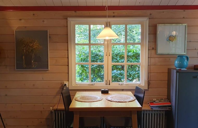 Dining table by window in Holiday home in 't Haantje, Drenthe, overlooking green garden.
