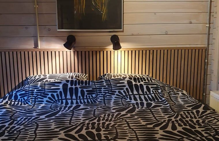 Comfortable bed in Cottage in 't Haantje, Drenthe, with atmospheric lighting.
