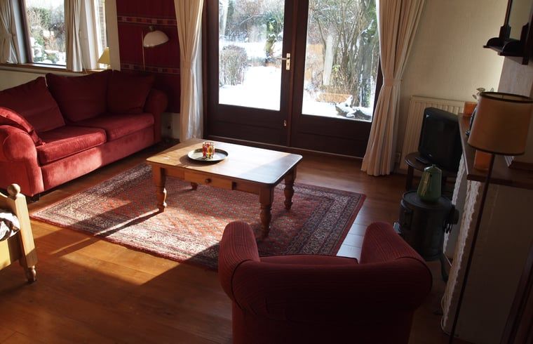 Comfortabele woonkamer met rood interieur in Vakantiehuis in Odoornerveen, Zuidoost Drenthe, Drenthe.