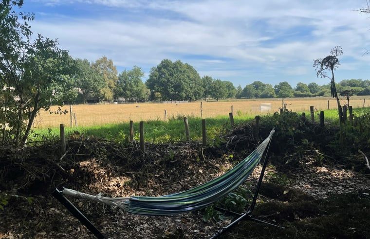 Ontspan in de hangmat bij Vakantiehuisje in Doldersum, Zuidwest Drenthe, met uitzicht op weidse velden en natuur.