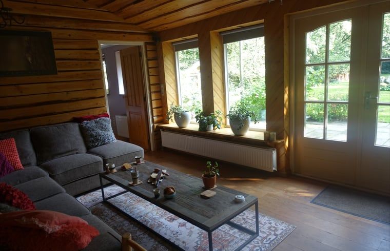Gezellige woonkamer van Huisje in Zuidwolde, vakantiehuis in Zuidwolde, Drenthe, met houten interieur en uitzicht op de tuin.