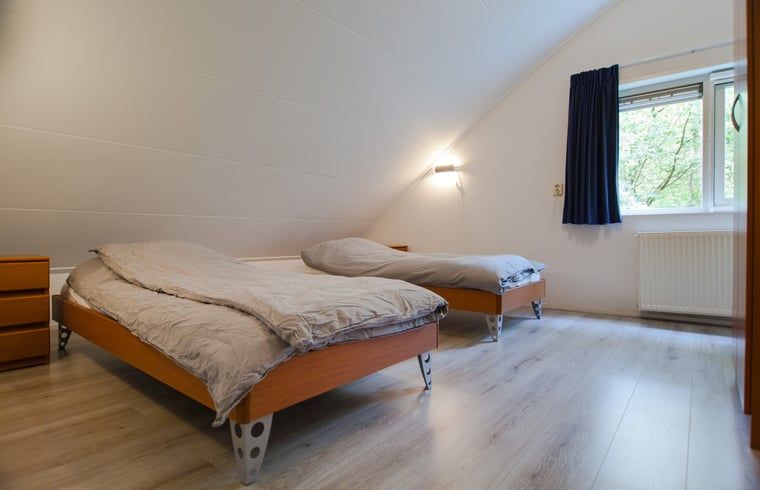 Gemuetliches Schlafzimmer im Ferienhaus in Ruinen, Drenthe, mit zwei bequemen Betten und Blick auf die gruene Umgebung.