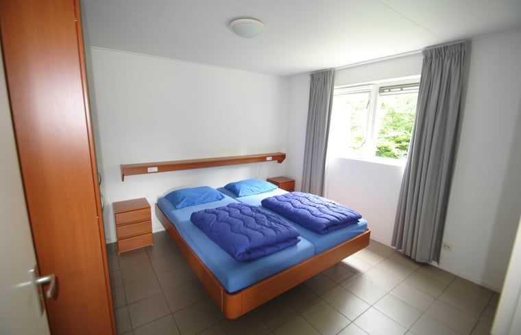 Geraeumiges Schlafzimmer im Ferienhaus in Ruinen, Suedwest-Drenthe, mit bequemem Doppelbett und Blick auf die gruene Umgebung.