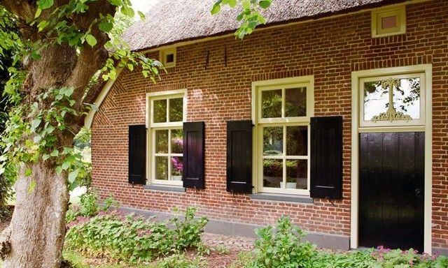 Charmantes Ferienhaus Hoeve den Anholt in Ruinen, Drenthe, mit traditioneller Backsteinfassade und gruener Umgebung.