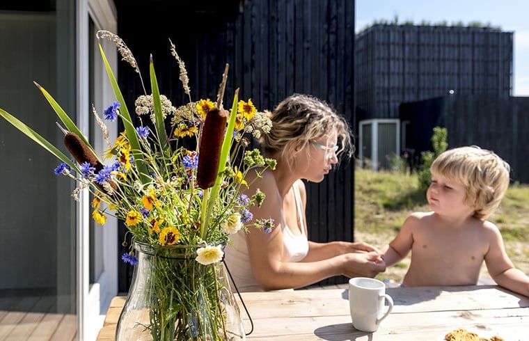 Moeder en kind op terras van Huisje in Wapserveen, vakantieaccommodatie in Drenthe met bloemen.