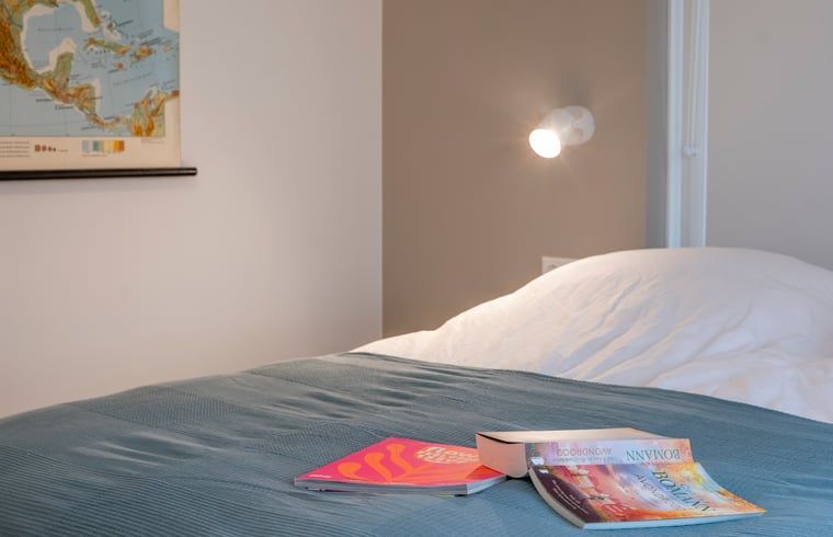 Slaapkamer in Vakantiehuisje in Dwingeloo, Zuidwest Drenthe, met comfortabel bed en leesmateriaal.