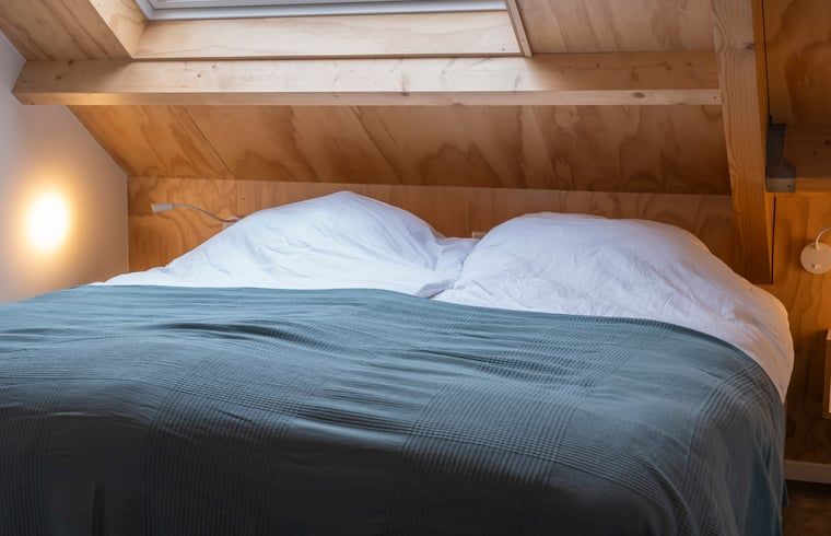 Knusse slaapkamer in Vakantiehuisje in Dwingeloo, Drenthe, onder een houten dak.