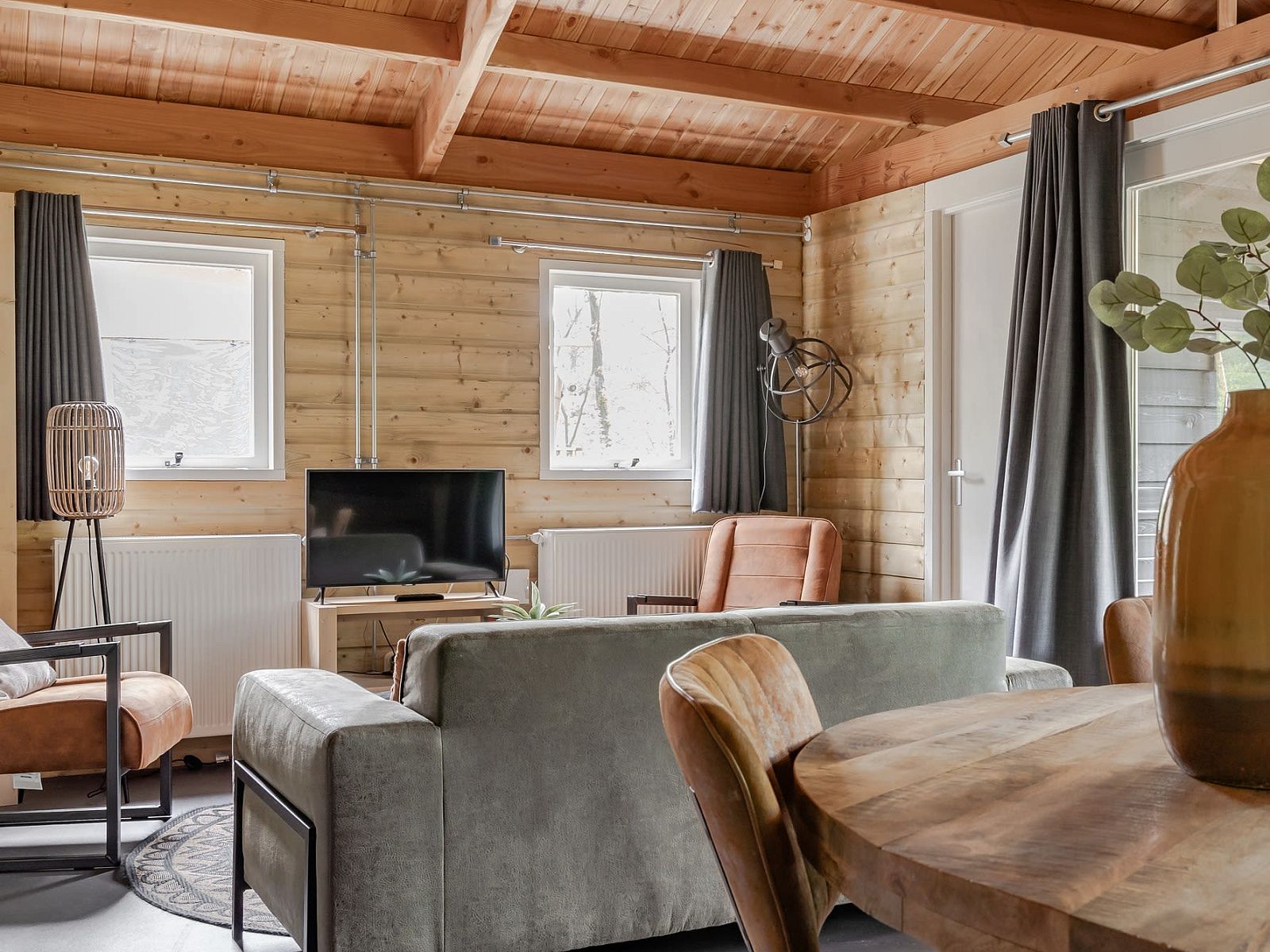 Cozy living room of Hooiberglodge in Dwingeloo, Southwest Drenthe. Enjoy a cozy vacation home with wooden interior and comfortable seating area.