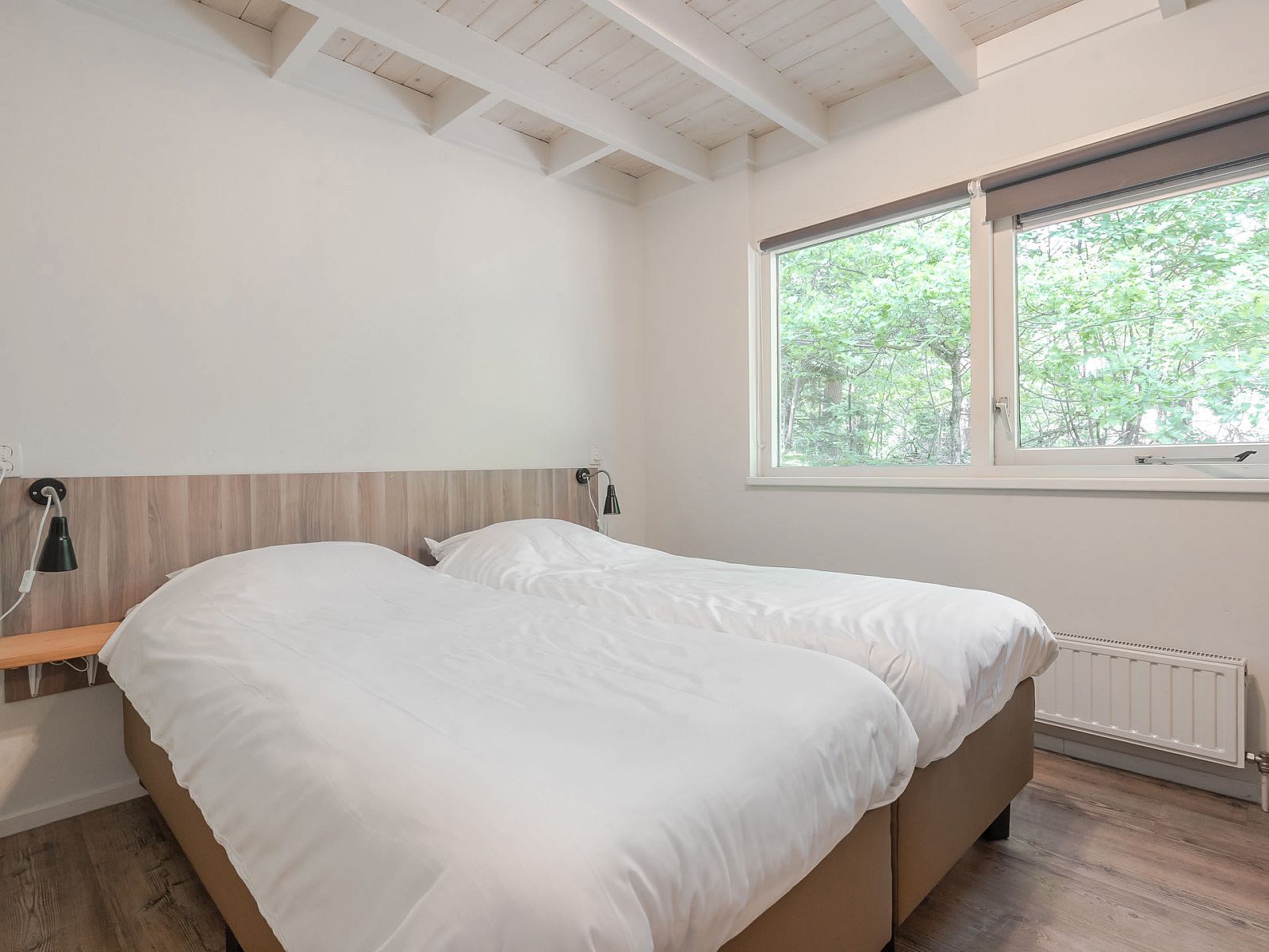 Gezellige slaapkamer in Bungalow Maan, een vakantiehuis in Dwingeloo, Zuidwest Drenthe, met uitzicht op de groene natuur.