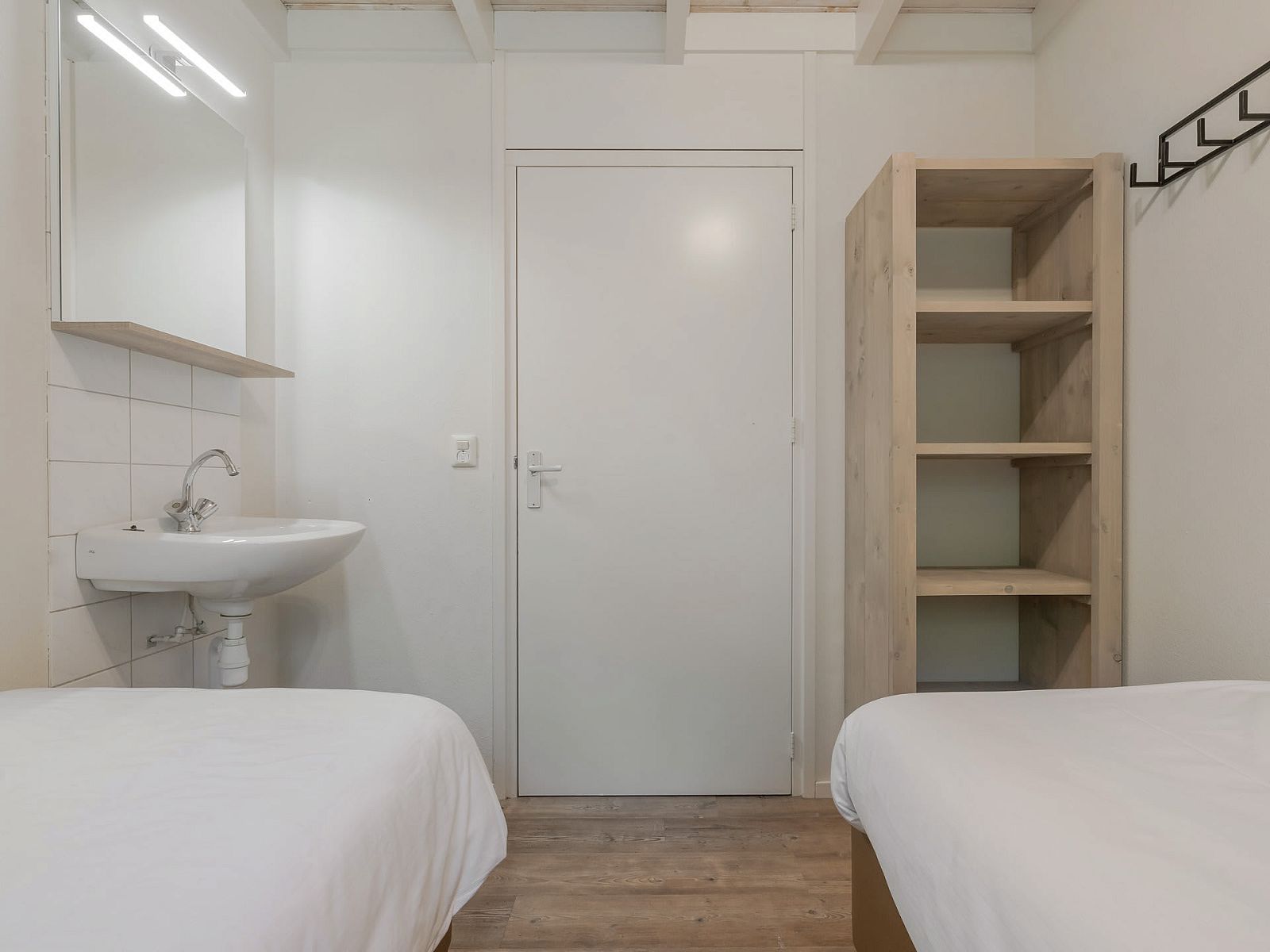 Sfeervolle slaapkamer in Bungalow Maan, vakantiehuis in Dwingeloo, Zuidwest Drenthe, met comfortabele bedden en moderne wastafel.