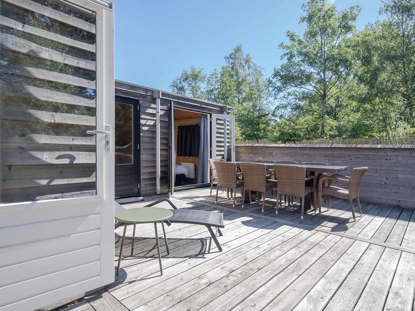 Enjoy the spacious wooden veranda of Heidelodge in Dwingeloo, Southwest Drenthe, perfect for relaxation in a natural setting.