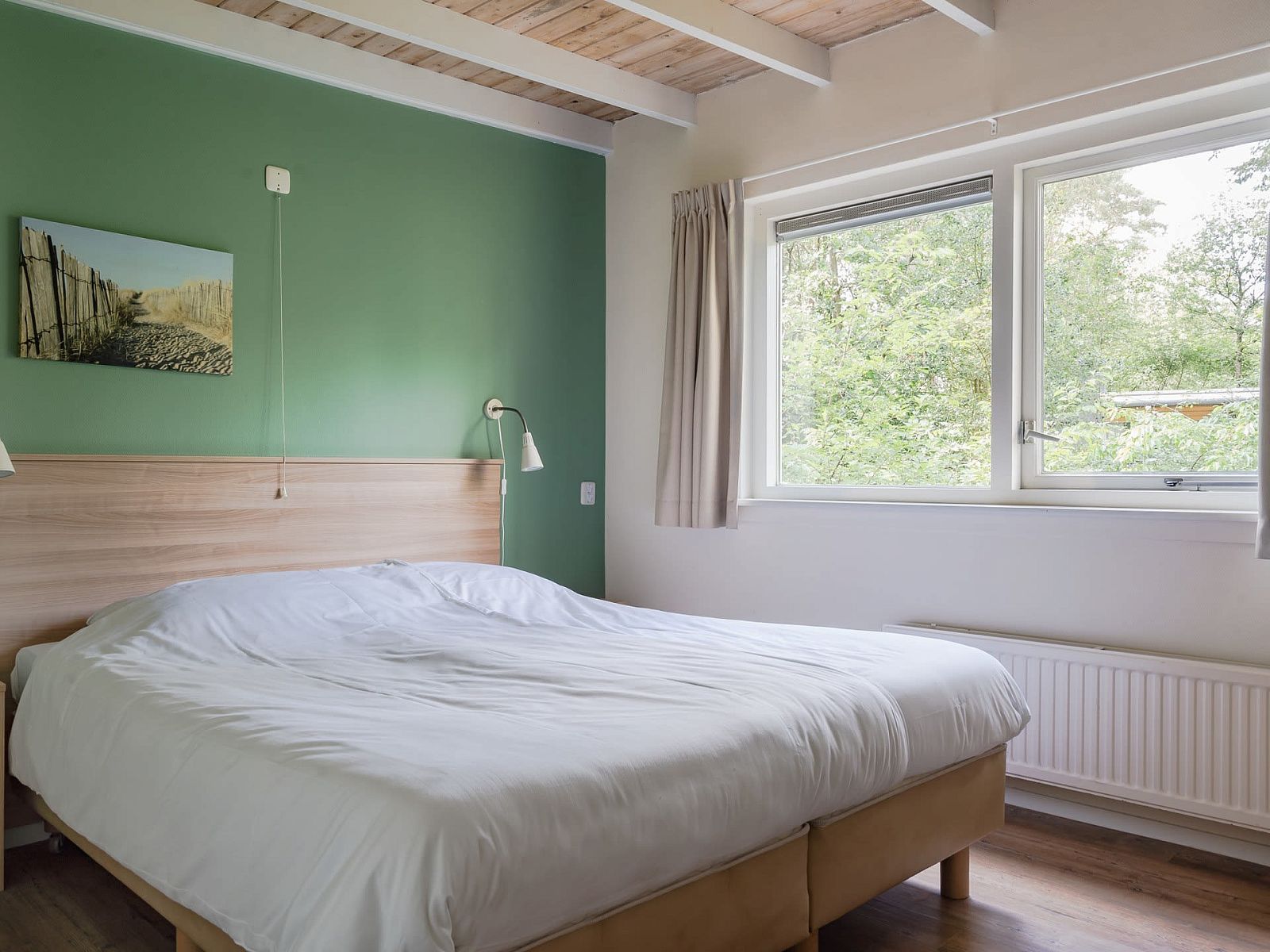 Slaapkamer in Bungalow Saturnus, Dwingeloo, Zuidwest Drenthe, met uitzicht op de natuur voor een rustgevend verblijf in een vakantiehuis.