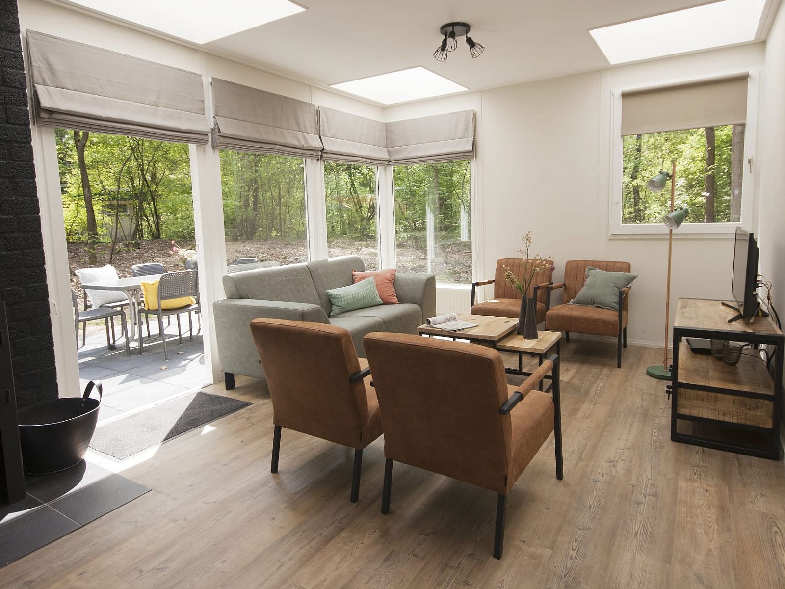 Gezellige woonkamer van Bungalow Mercurius in Dwingeloo, Zuidwest Drenthe, met uitzicht op het bosrijke terras.