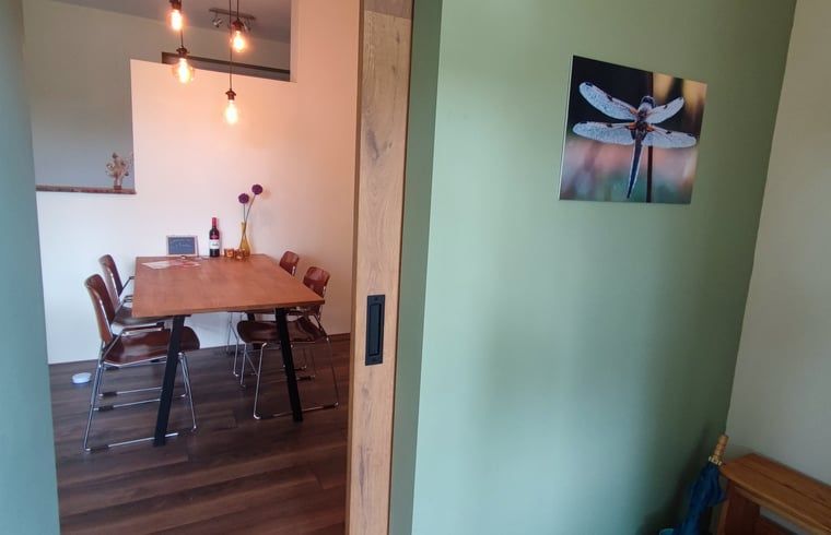 Blick in den Essbereich des Ferienhauses in Dwingeloo, Suedwest-Drenthe, mit stimmungsvoller Beleuchtung und Kunst an der Wand.