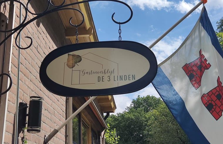 Eingang zum Ferienhaus in Dwingeloo, Suedwest-Drenthe, mit einladendem Schild und Fahnen.