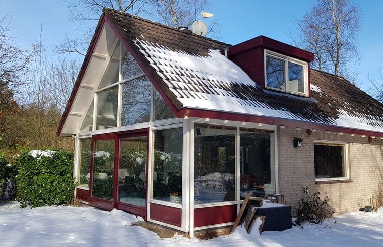 Winterse sfeer bij Vakantiehuis in Zorgvlied, Zuidwest Drenthe, met besneeuwd dak en grote ramen.
