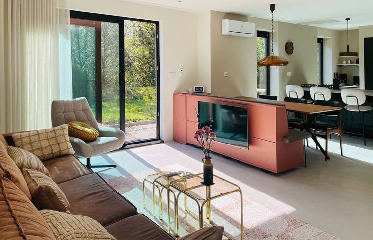 Modern living room of Holiday Home in Zorgvlied, Southwest Drenthe, overlooking green nature through large windows.