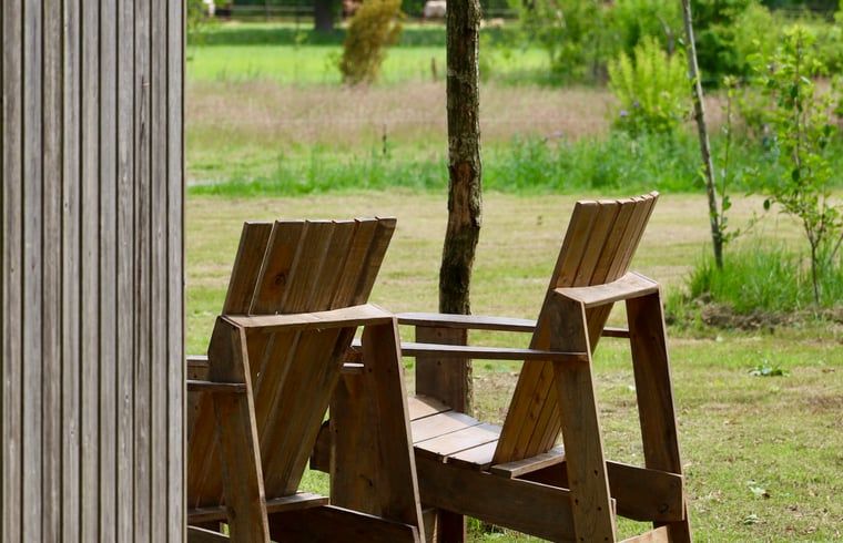 Wooden chairs on the terrace of Holiday Home in Vledder, Southwest Drenthe, overlooking nature.