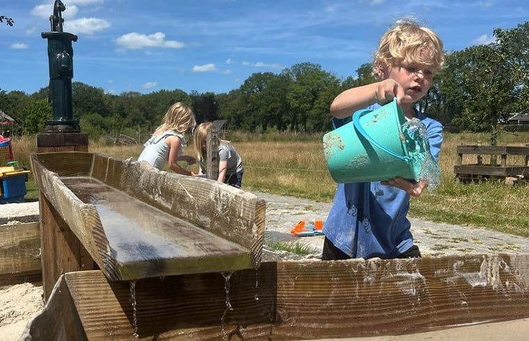 Children play with water at Holiday Home in Vledder, southwest Drenthe, on sunny day.