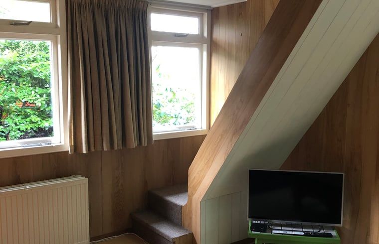 Knusse woonkamer van Huisje in Wateren, Westerveld, met houten interieur en uitzicht op de groene omgeving in Zuidwest Drenthe.
