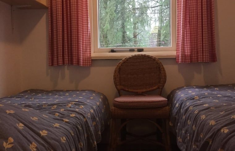 Schlafzimmer mit Doppelbett in einem Ferienhaus in Wateren, Westerveld, mit Blick auf den Garten in Drenthe.