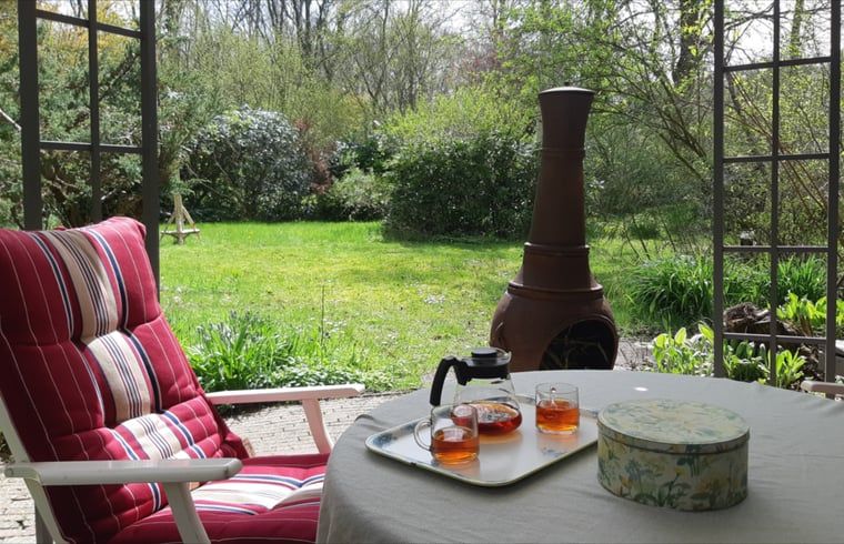 Cozy porch of Huisje in Koekange, cottage in Southwest Drenthe, with tea and garden views.