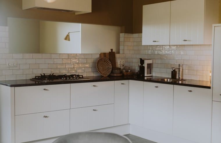 Moderne Kueche eines Ferienhauses in Uffelte, Suedwest-Drenthe, mit weissen Schraenken und sauberer Verarbeitung.