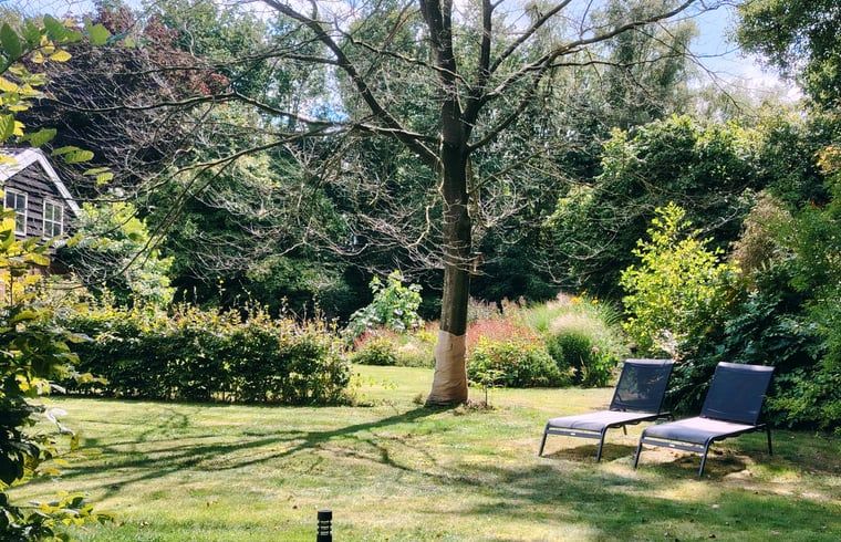 Tuin van Huisje in Elim, vakantiehuis in Elim, Zuidwest Drenthe, met ligstoelen en veel groen.
