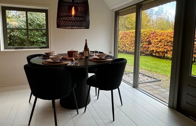 Essecke im Ferienhaus in Ansen, Suedwest-Drenthe mit Blick auf den Garten.