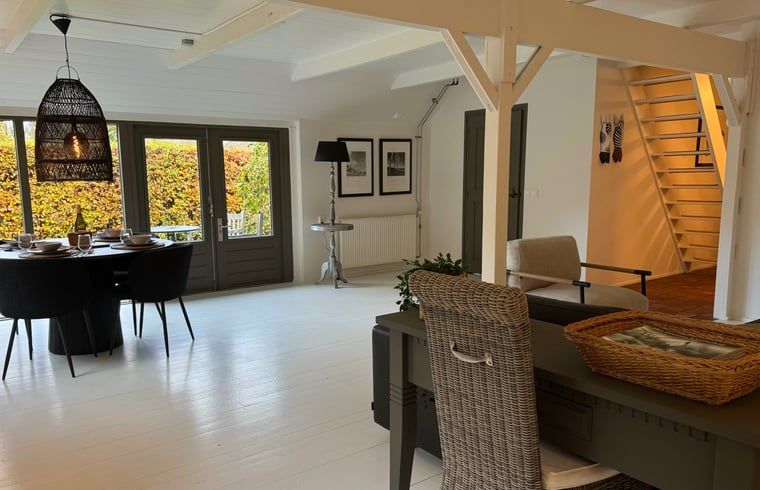 Geraeumiges Wohnzimmer des Ferienhauses in Ansen, Suedwest-Drenthe, mit offener Treppe.