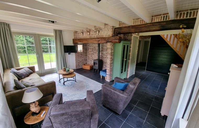 Gemuetliches Wohnzimmer des Ferienhauses in Oude Willem, Suedwest-Drenthe, mit Holzbalken und modernen Moebeln.
