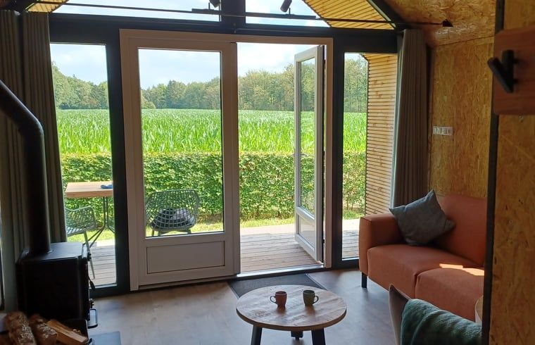 Ruime binnenruimte van vakantiehuis Huisje in Hollandscheveld met uitzicht op natuur.