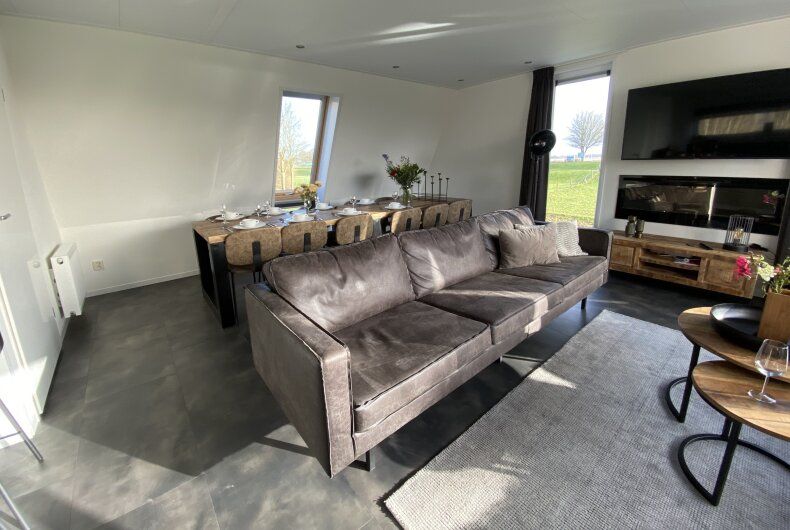 Modern living room of detached house in Biddinghuizen, vacation home in Flevoland with comfortable seating area and view of the garden.