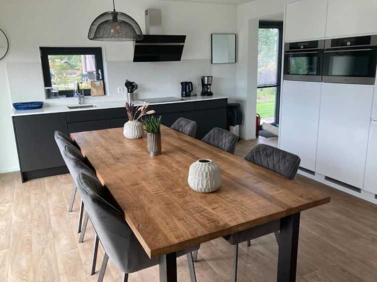 Stijlvolle eetruimte in Vakantiehuis Cube Elite 6, Biddinghuizen, Flevoland met grote houten tafel en moderne keuken.