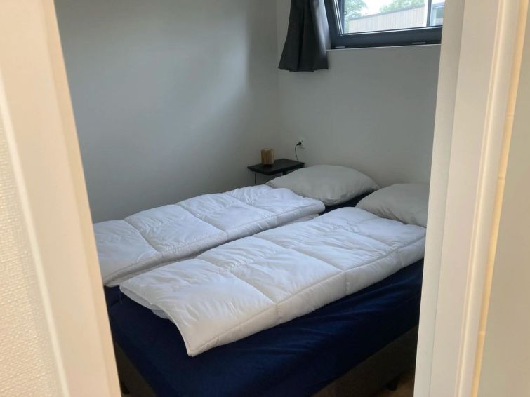 Tweede slaapkamer in Vakantiehuis Cube Elite 6, Biddinghuizen, Flevoland met comfortabel bed en natuurlijk licht.
