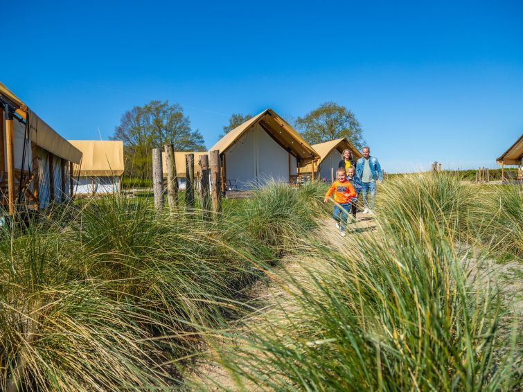 Gezin wandelt door duinen bij glamping tenten in de buurt van Vakantiehuis Cube Elite 6, Biddinghuizen, Flevoland.