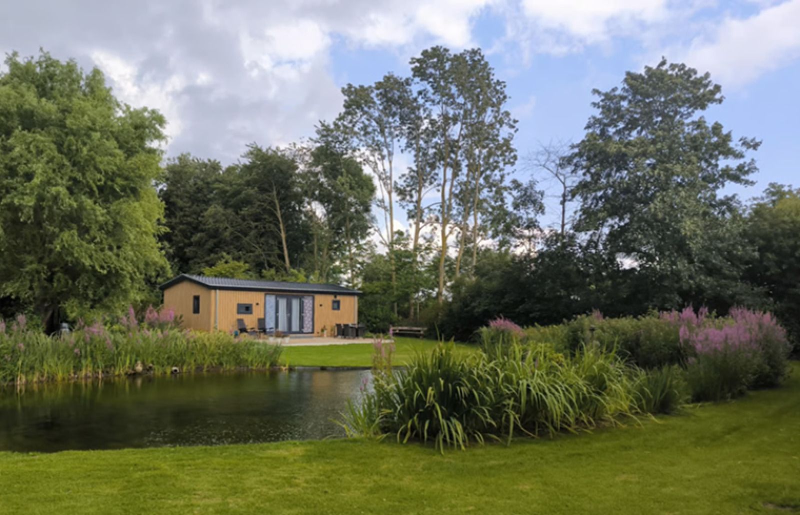 Ferienhaus FL088 in Kraggenburg, Ost-Flevoland, umgeben von ueppiger Natur und einem ruhigen Teich fuer einen entspannten Aufenthalt.