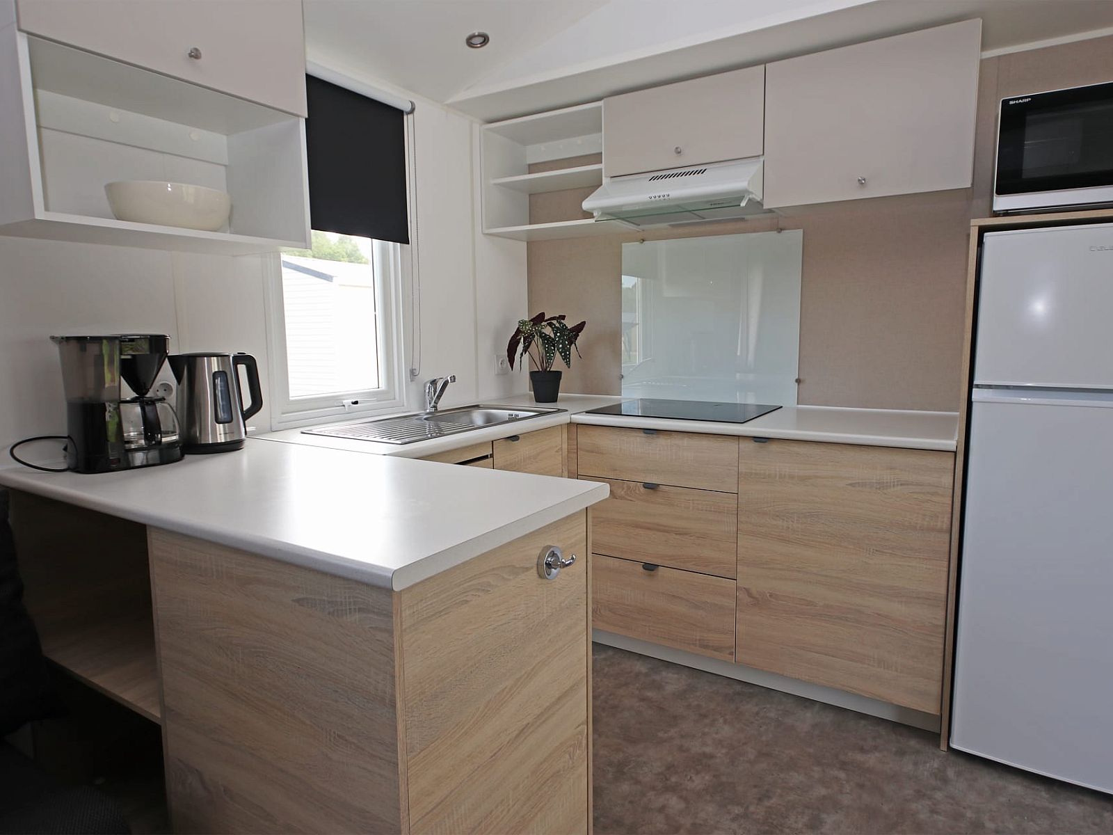 Moderne keuken in Chalet de Krooneend, een stacaravan in Zeewolde, Zuidelijk Flevoland, met stijlvolle kasten en apparatuur.