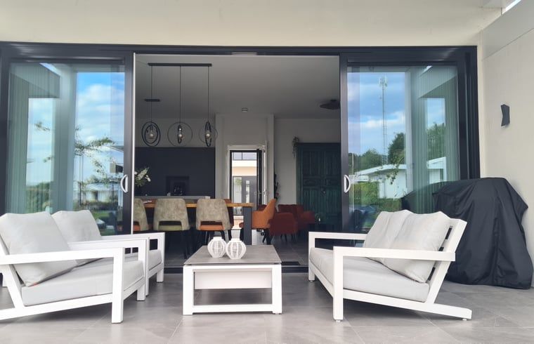 Geraeumige Veranda des Ferienhauses in Zeewolde mit bequemen Stuehlen.