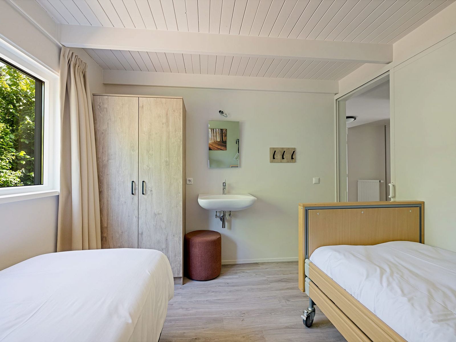 Slaapkamer in Aangepaste bungalow de Dobbe, Appelscha, met twee bedden en uitzicht op de Friese bossen in Friesland.