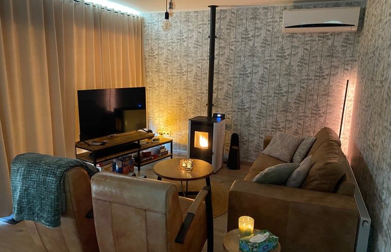 Gemuetliches Wohnzimmer des Ferienhauses in Appelscha, mit stimmungsvoller Beleuchtung und Kaminofen, in den friesischen Waeldern gelegen.