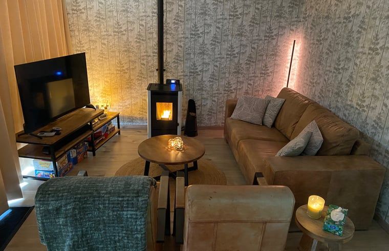 Ferienhaus in Appelscha, gemuetliche Sitzecke mit Kaminofen und komfortablen Moebeln in den friesischen Waeldern, Friesland.