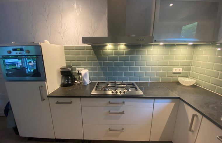 Stilvolle Kueche im Ferienhaus in Appelscha, mit modernen Geraeten und gruenen Fliesen in Friesland.