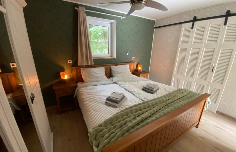 Ferienhaus in Appelscha, gemuetliches Schlafzimmer mit Holzmoebeln und Blick auf die friesische Landschaft.