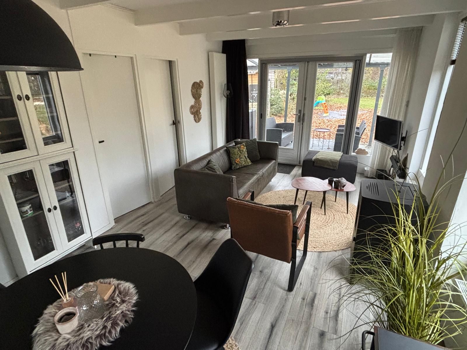 Gemuetliches Wohnzimmer von Bungalow het Goudhaantje in Appelscha, Friesland, mit Blick auf die friesischen Waelder und einer komfortablen Sitzecke.