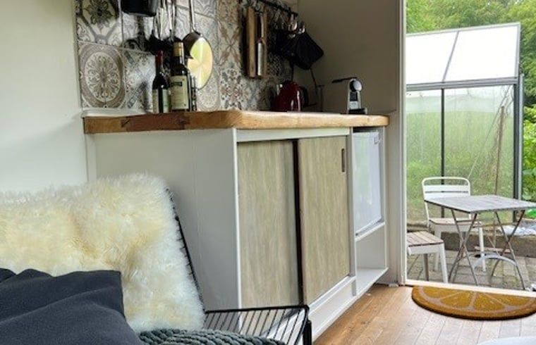 Innenbereich des Ferienhauses in Appelscha mit gemuetlicher Sitzecke und Blick auf die gruene Umgebung.