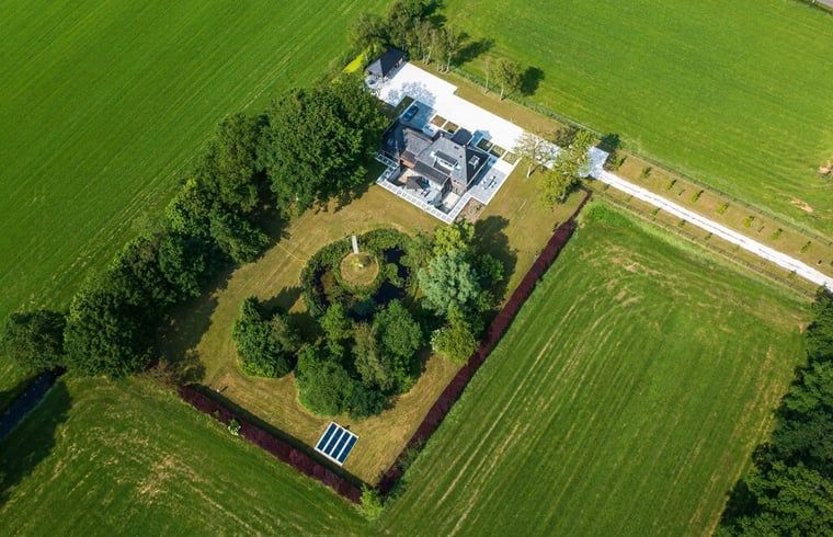 Luchtfoto van vakantiehuisje in Bakkeveen, Friesland, te midden van groene velden.
