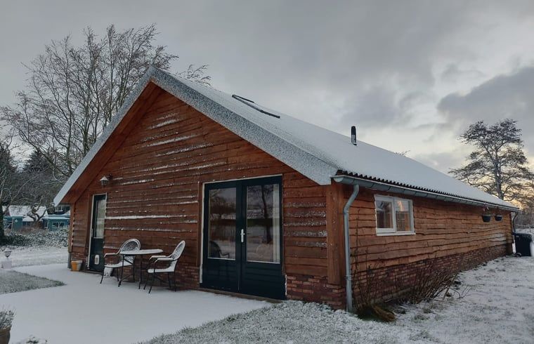 Sneeuw bedekt Vakantiehuis in Haulerwijk, een winterwonderland in Friesland.