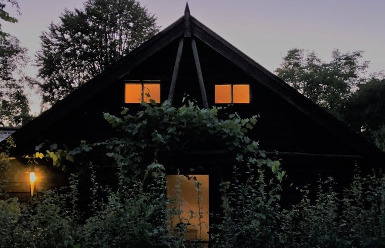 Vakantiehuisje in Boijl verlicht in de avond, omgeven door de rustgevende natuur van Friesland.