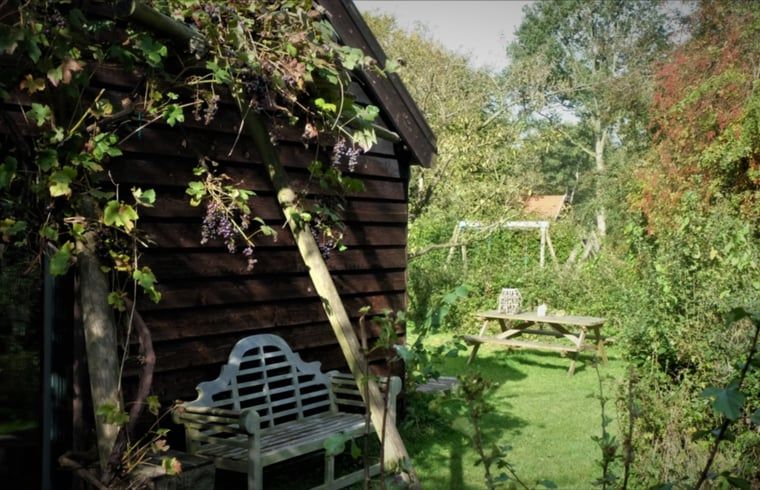 Tuinhoek met bankje bij Vakantiehuisje in Boijl, een groene oase in Friesland.